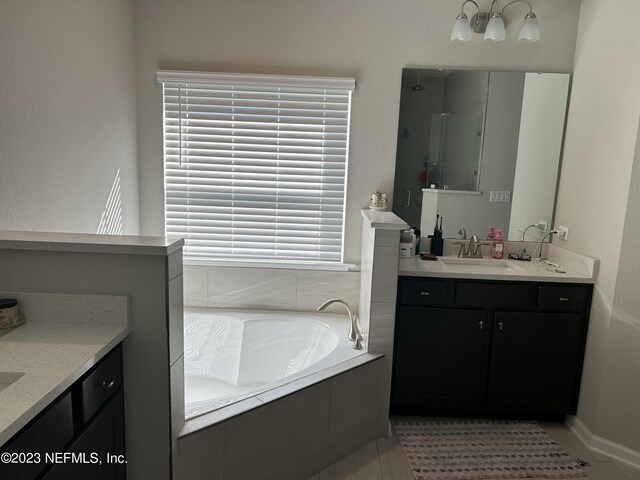 bathroom featuring tiled tub, vanity, and tile patterned flooring