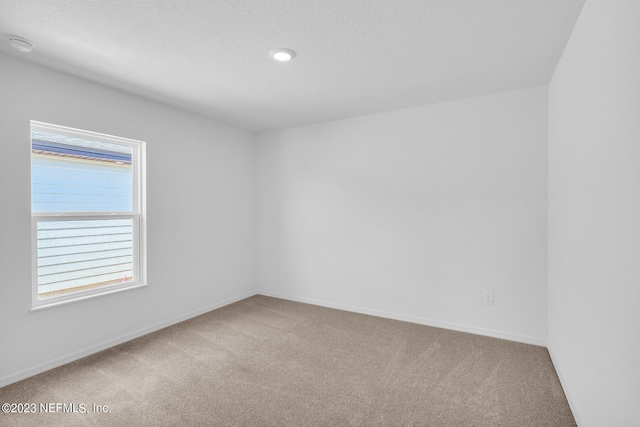 empty room with carpet floors, a textured ceiling, and baseboards