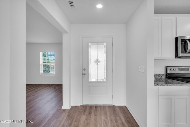 entryway with baseboards, visible vents, and wood finished floors