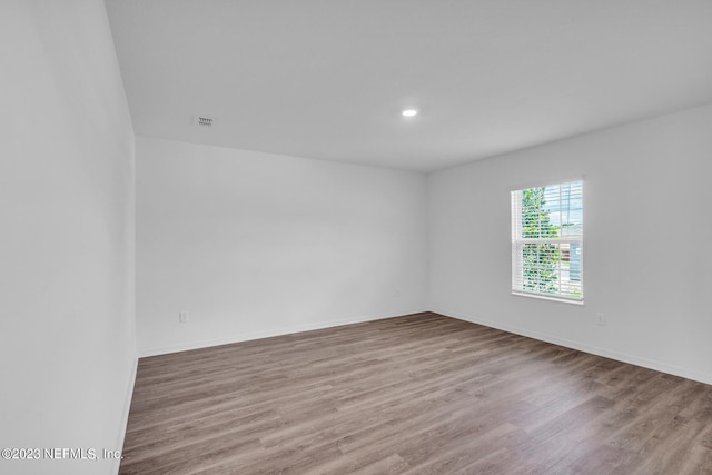 unfurnished room featuring recessed lighting, wood finished floors, and baseboards