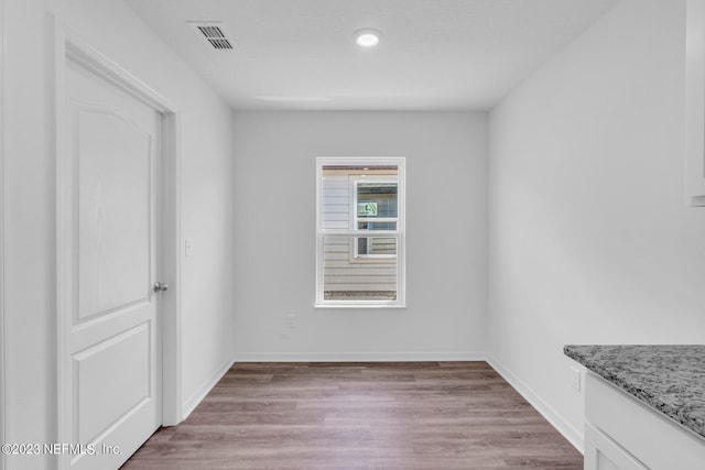 spare room featuring light wood-style floors, visible vents, and baseboards