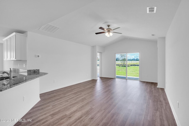 unfurnished living room with ceiling fan, dark wood-type flooring, a sink, visible vents, and vaulted ceiling