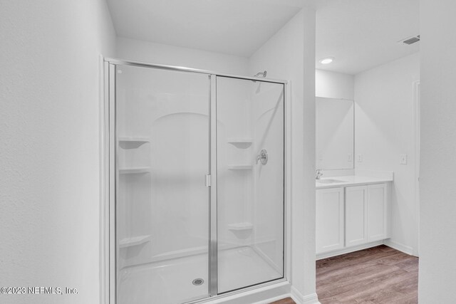 full bathroom with a stall shower, baseboards, wood finished floors, and vanity