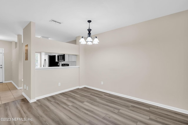 unfurnished dining area with a chandelier and wood-type flooring