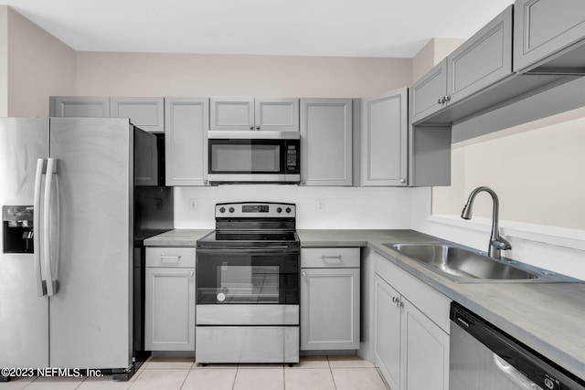 kitchen with gray cabinetry, sink, tasteful backsplash, light tile patterned flooring, and stainless steel appliances