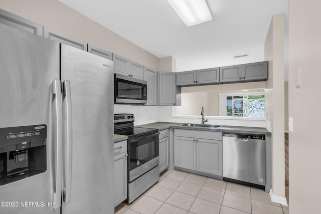 kitchen featuring gray cabinets, sink, light tile patterned floors, and appliances with stainless steel finishes