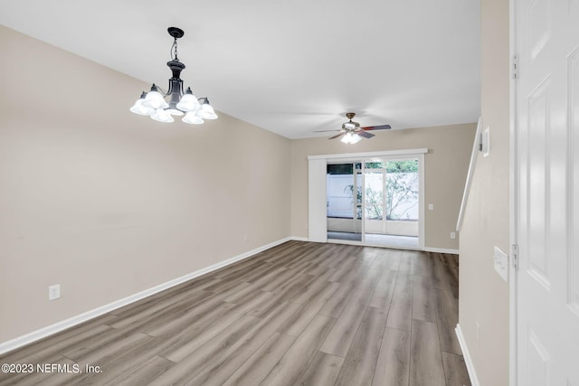 unfurnished room with ceiling fan with notable chandelier and light hardwood / wood-style floors