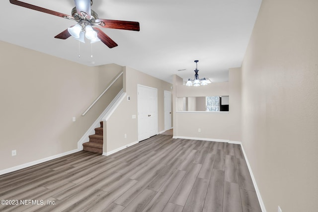 unfurnished living room with light hardwood / wood-style floors and ceiling fan with notable chandelier