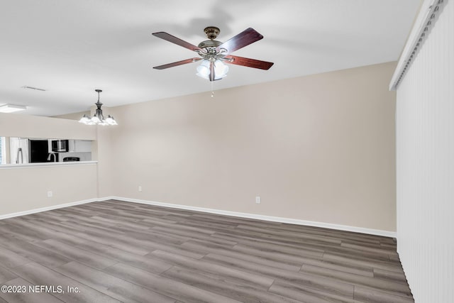 empty room with hardwood / wood-style floors and a notable chandelier