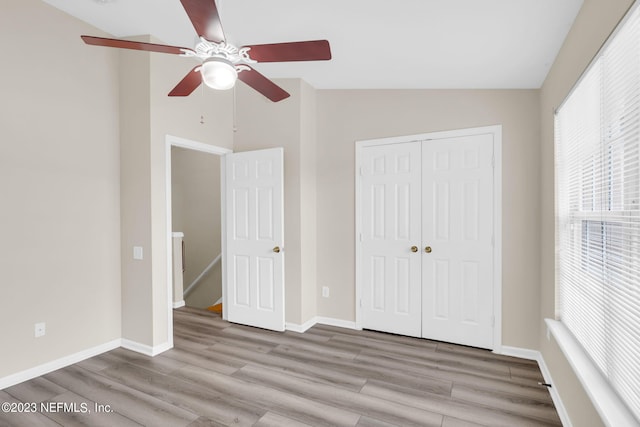 unfurnished bedroom featuring ceiling fan, a closet, vaulted ceiling, and light wood-type flooring