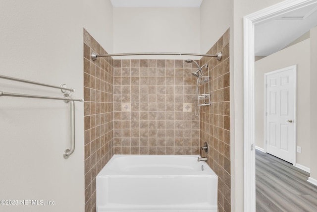 bathroom with hardwood / wood-style floors and tiled shower / bath