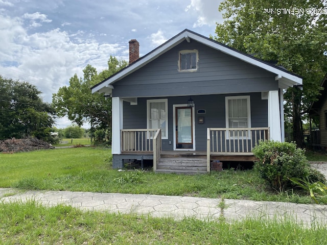 bungalow-style home with covered porch and a front yard