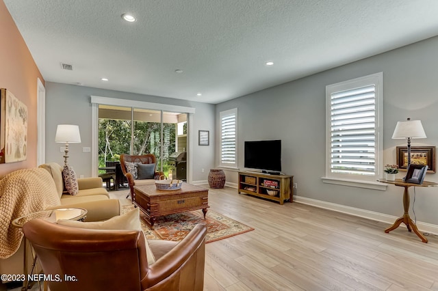 living room with a textured ceiling, a wealth of natural light, and light hardwood / wood-style flooring