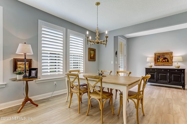 dining area with a textured ceiling and light hardwood / wood-style flooring