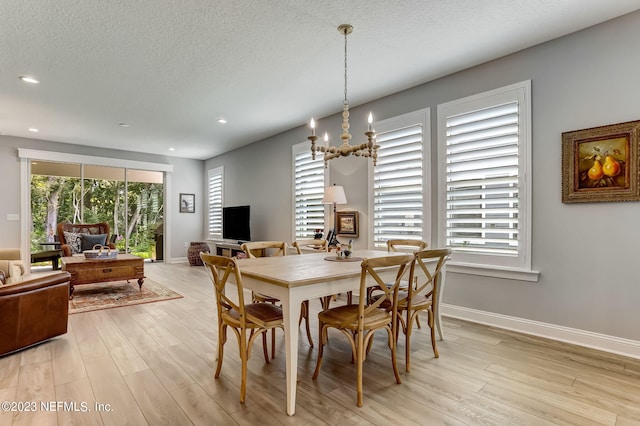 dining space with plenty of natural light, light wood-type flooring, and a textured ceiling