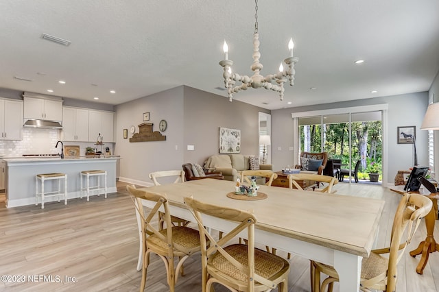 dining space with light hardwood / wood-style floors and an inviting chandelier