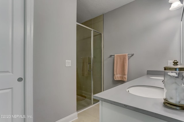 bathroom featuring tile patterned flooring, vanity, a shower with shower door, and a textured ceiling