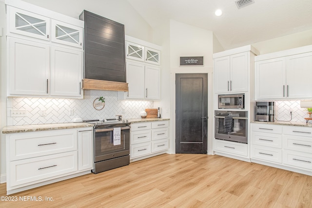 kitchen with lofted ceiling, white cabinets, range hood, light hardwood / wood-style floors, and stainless steel appliances