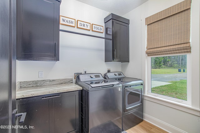 washroom featuring separate washer and dryer, cabinets, a textured ceiling, and light hardwood / wood-style floors