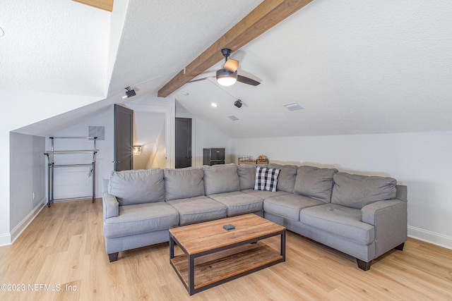 living room with a textured ceiling, vaulted ceiling with beams, light hardwood / wood-style floors, and ceiling fan