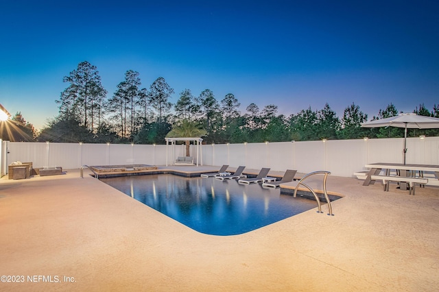 pool at dusk featuring a patio