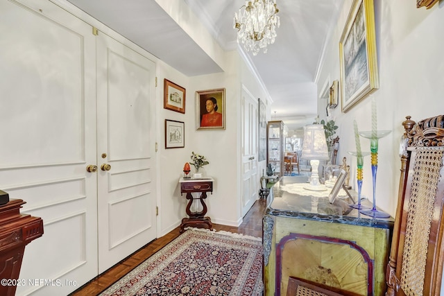 foyer entrance with crown molding, dark wood-type flooring, and a chandelier