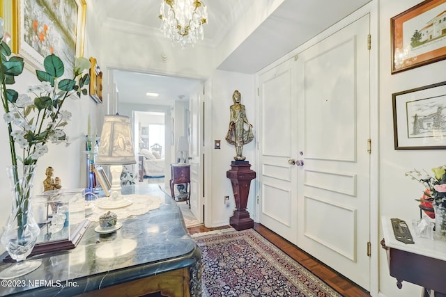 foyer entrance featuring a notable chandelier, dark hardwood / wood-style flooring, and crown molding