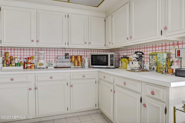 kitchen with white cabinets, light tile patterned floors, and tasteful backsplash