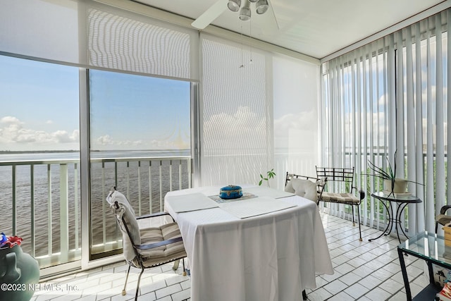 sunroom / solarium with ceiling fan and a water view