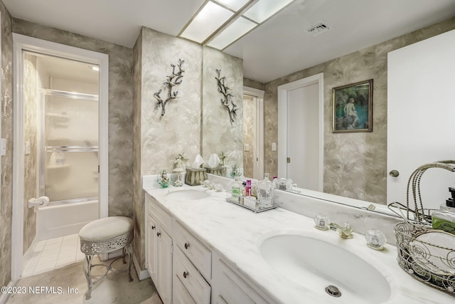 bathroom with tile patterned flooring, vanity, and bath / shower combo with glass door