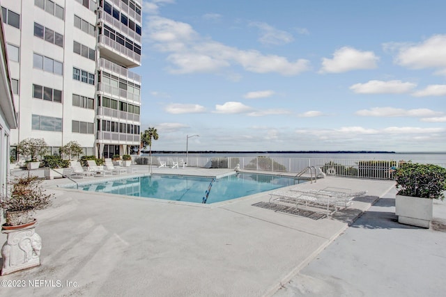 view of swimming pool featuring a patio area and a water view