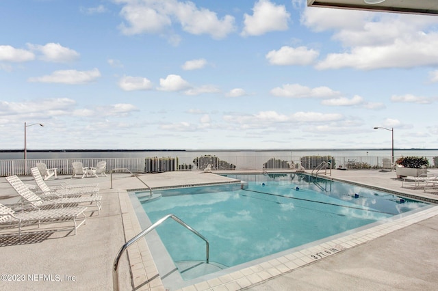 view of swimming pool featuring a water view and a patio