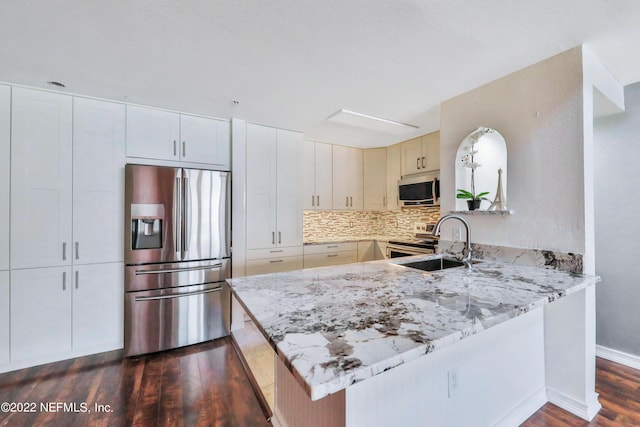 kitchen featuring light stone countertops, appliances with stainless steel finishes, and kitchen peninsula