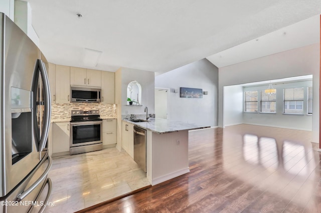 kitchen featuring appliances with stainless steel finishes, tasteful backsplash, sink, kitchen peninsula, and cream cabinets