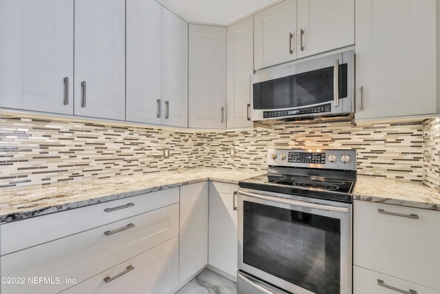 kitchen with white cabinetry, appliances with stainless steel finishes, light stone counters, and decorative backsplash