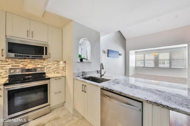 kitchen with sink, kitchen peninsula, stainless steel appliances, light stone countertops, and backsplash