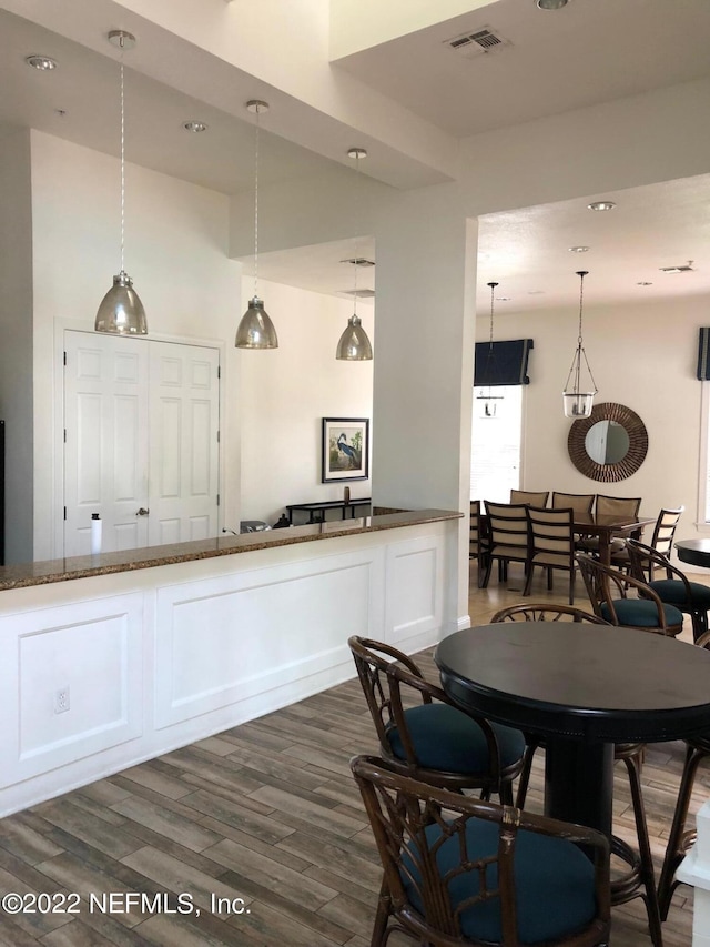 kitchen with white cabinetry, hanging light fixtures, dark hardwood / wood-style flooring, and dark stone countertops