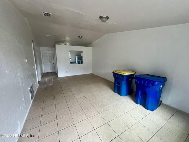 interior space featuring light tile patterned floors, visible vents, and lofted ceiling