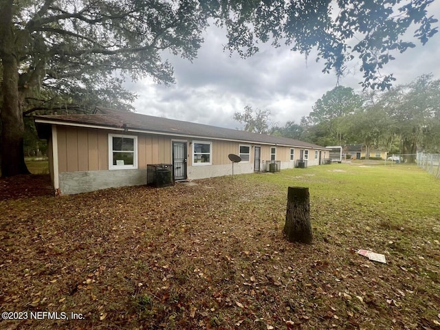 back of property featuring central AC, a yard, and fence