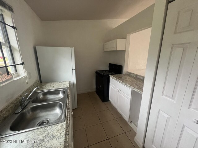 kitchen with electric range, sink, white cabinets, and light tile patterned flooring