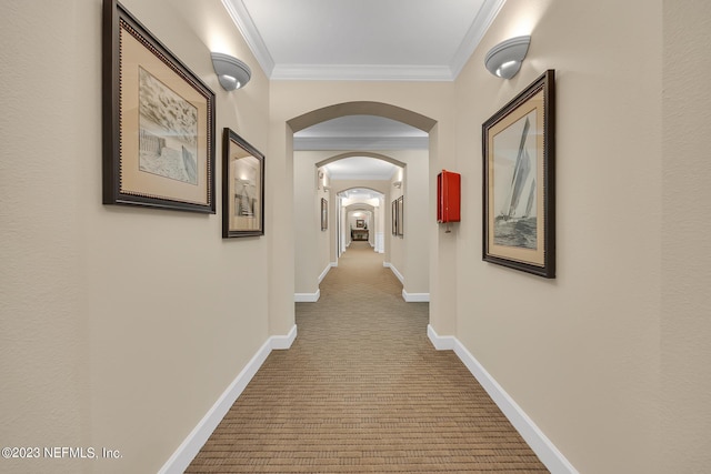 hall with ornamental molding, arched walkways, carpet floors, and baseboards