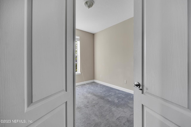 carpeted empty room featuring baseboards