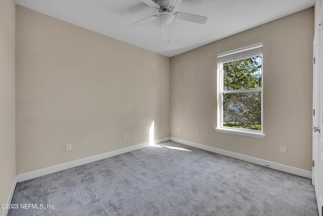 spare room with light carpet, ceiling fan, and baseboards