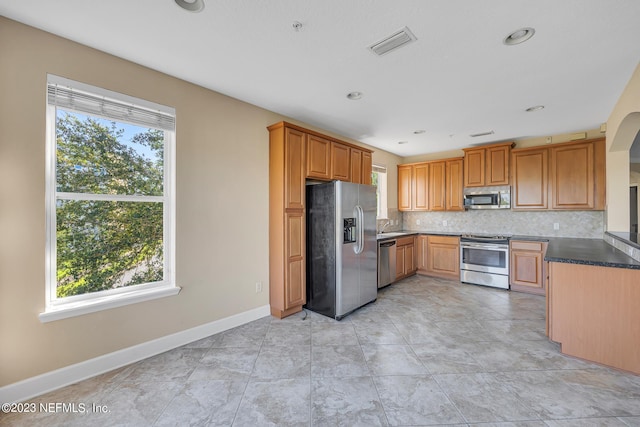 kitchen with appliances with stainless steel finishes, sink, tasteful backsplash, and light tile flooring