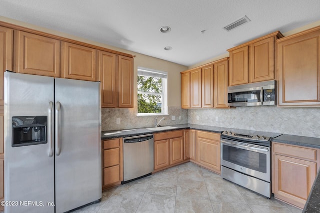 kitchen featuring stainless steel appliances, sink, tasteful backsplash, and light tile floors