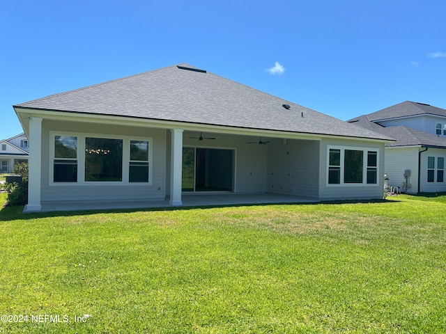 rear view of property featuring a shingled roof, a patio area, ceiling fan, and a lawn