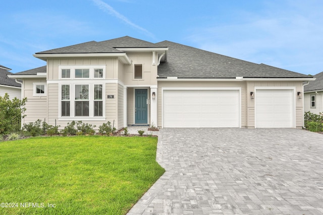 prairie-style home featuring a garage, decorative driveway, board and batten siding, and a front yard