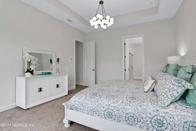 carpeted bedroom featuring a notable chandelier and a tray ceiling