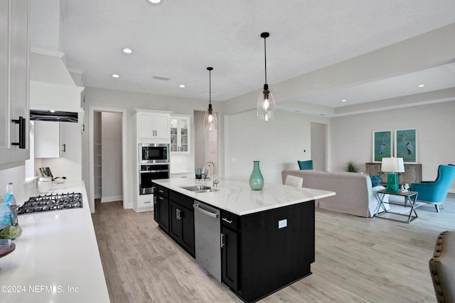 kitchen featuring appliances with stainless steel finishes, open floor plan, a kitchen island with sink, white cabinetry, and dark cabinetry