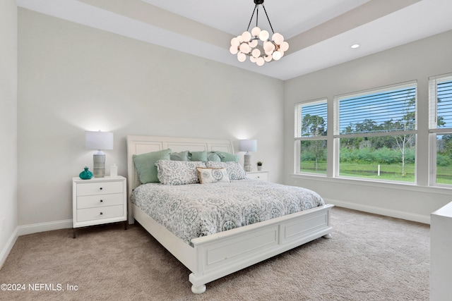 carpeted bedroom featuring a chandelier and a raised ceiling